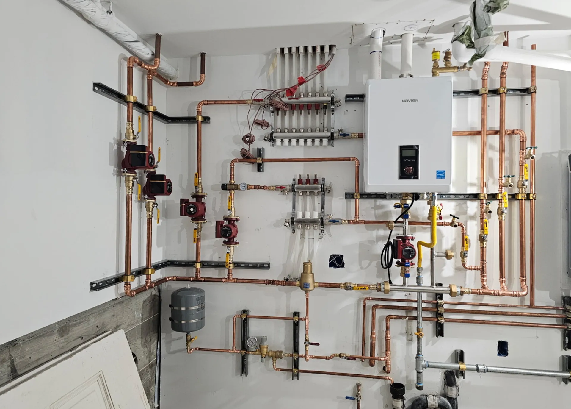 Wall mounted Navien condensing boiler and hydronic manifold