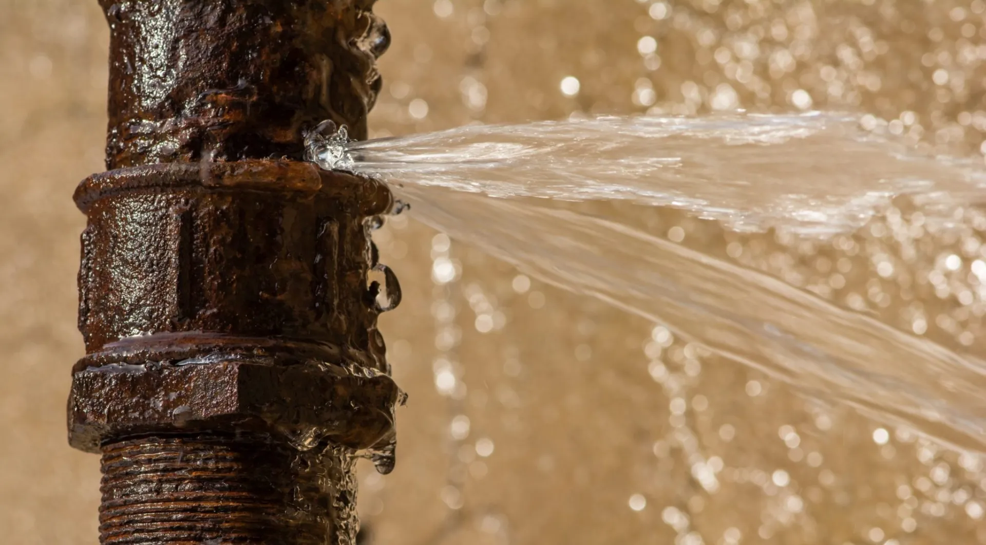 Water spraying from a corroded pipe fitting