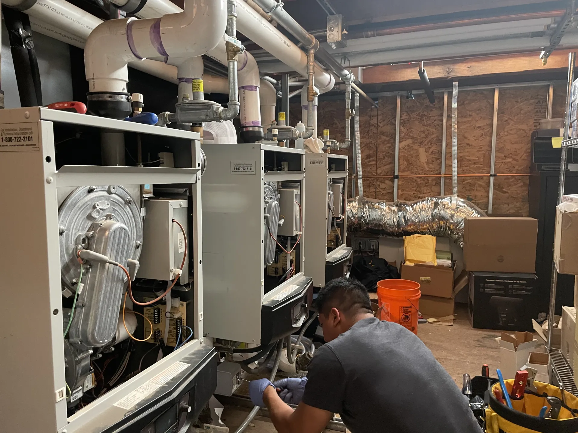 Technician servicing a row of commercial boilers in a mechanical room